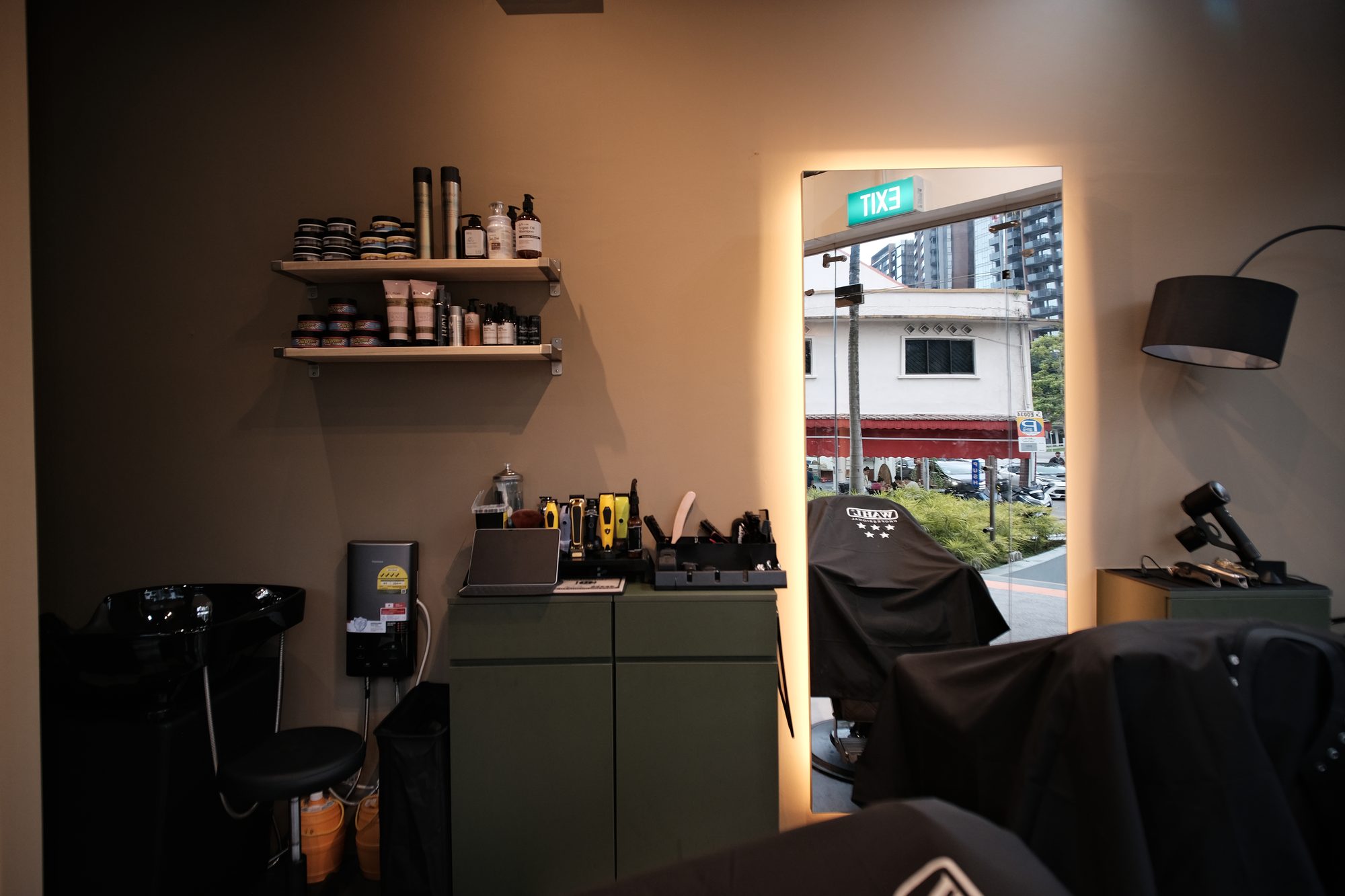 Warm toned barber shop interior with full height mirror and open shelving Singapore